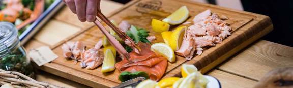 A wooden board with slices of salmon and lemon.